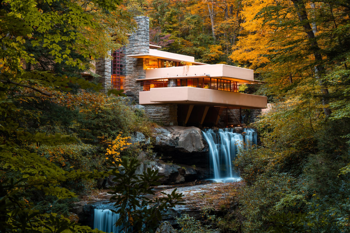 Fallingwater house surrounded by lush forest, perched over a waterfall, blending with natural surroundings