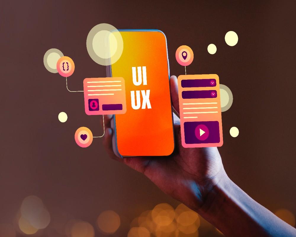 A UX designers hand holds a smartphone displaying UI UX on the screen. 