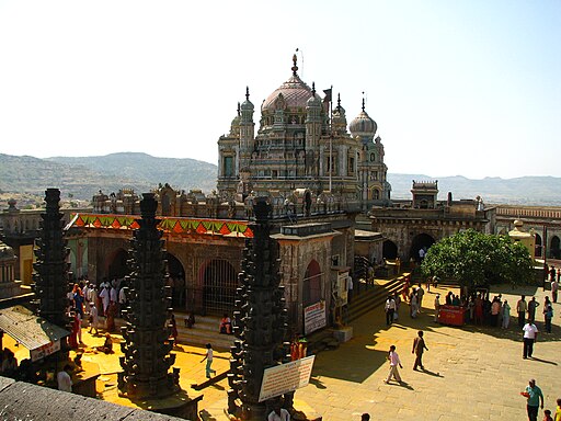 A historic temple showcasing stunning Maratha architecture stands against a backdrop of hills. 