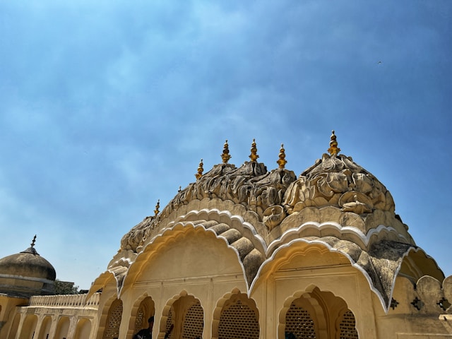 A historical building with ornate domes and arches in one of the captivating Indian cities. The architecture, perfect for heritage tourism or architectural walks, features intricate carvings and a pale stone facade, highlighting traditional design elements.