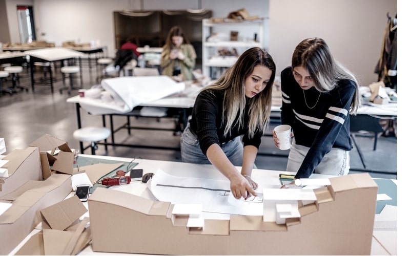 Graduate architecture student analyzing urban design models in studio.*