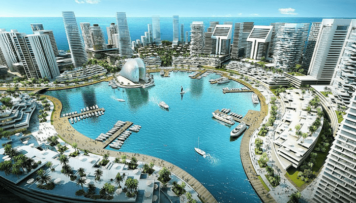 A futuristic coastal city, a landfill project, features a large harbor surrounded by modern high-rise buildings. Boats are docked along the curved waterfront. 