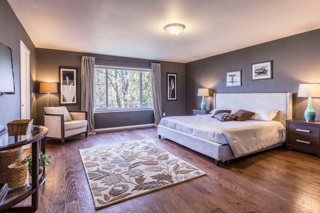 Modern bedroom with large window, wooden flooring, neutral walls, and cozy furnishings in natural light