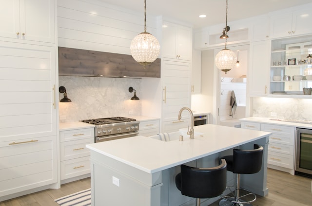 A modern kitchen with Vastu-friendly layout showcases white cabinets and marble countertops. 