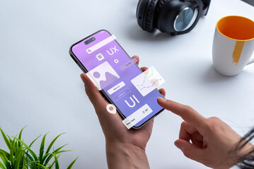 A person holding a phone showing UI-UX elements.