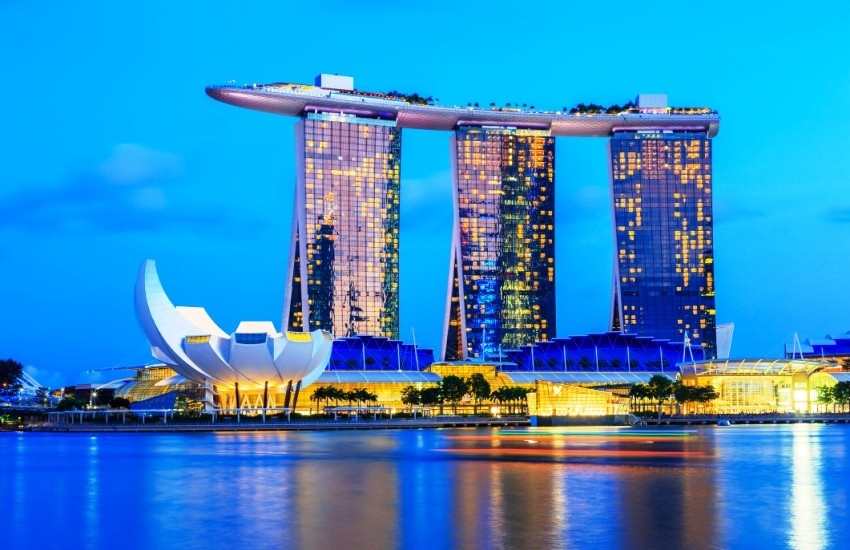 Night view of the Marina Bay Sands hotel, built on reclaimed land in Singapore, with its three towers and distinctive rooftop infinity pool. The ArtScience Museum, shaped like a lotus flower, is visible in the foreground.&nbsp;