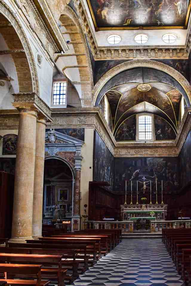 The interior of the historic church features ornate arches, columns, and intricate ceiling artwork supported by elegant pendentives. 