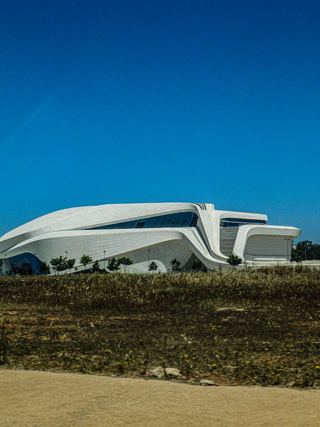 A futuristic white building with smooth, flowing curves against a clear blue sky epitomizes parametric design.