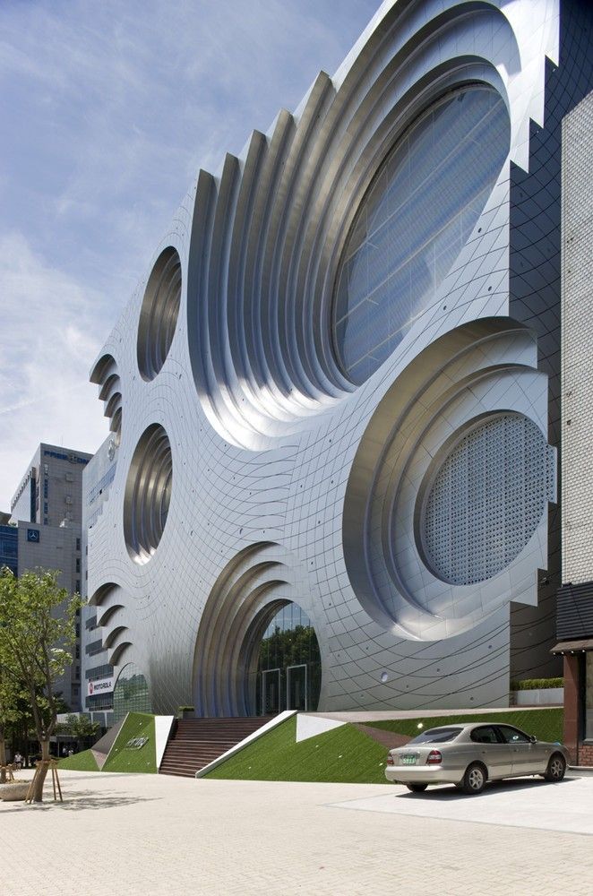 A parametric design building showcases large, circular, metallic patterns on its facade, creating a dynamic, rippled effect. 
