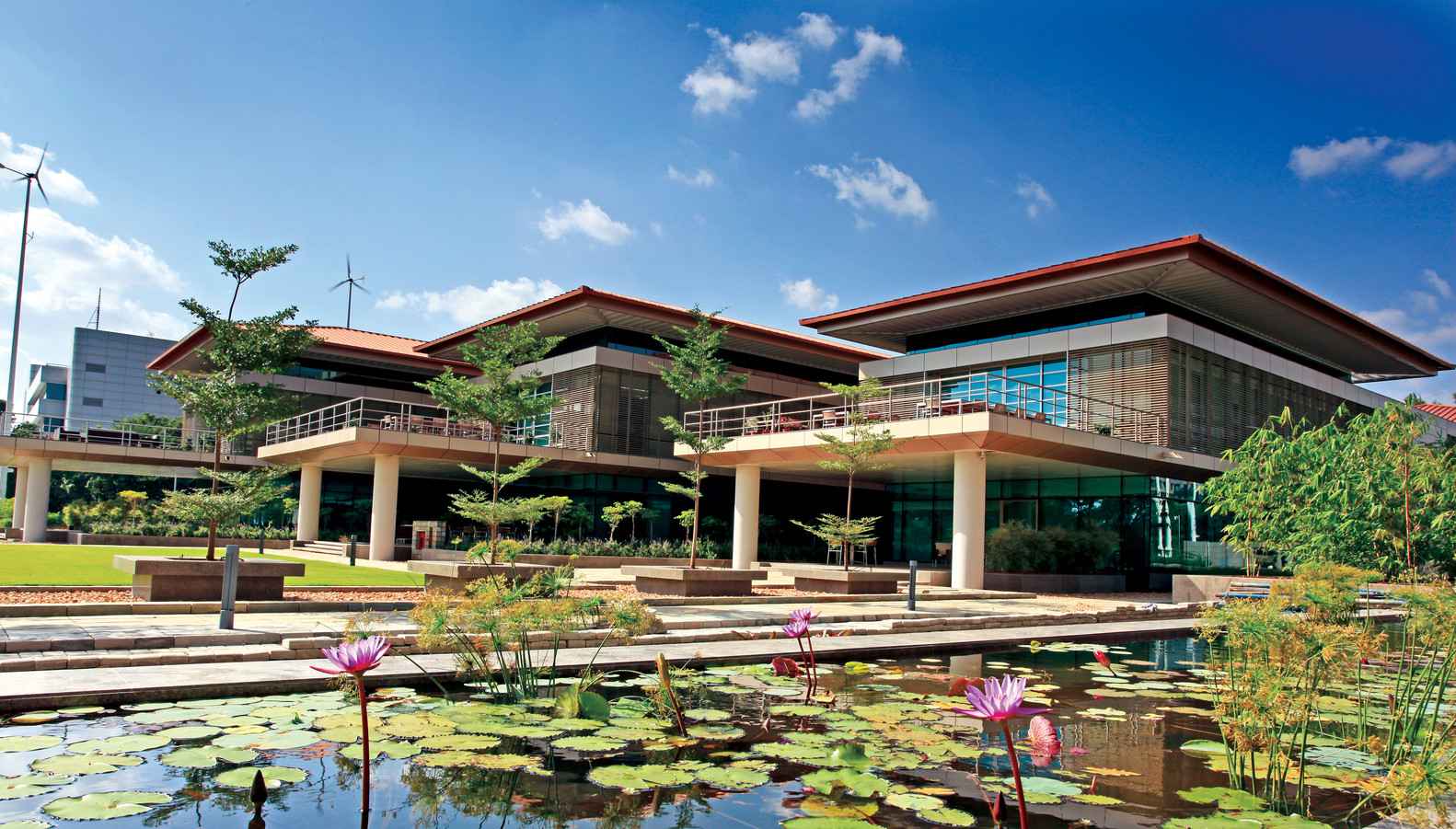 A modern building with large windows and overhanging roofs is surrounded by greenery, showcasing the architects' commitment to sustainability. 
