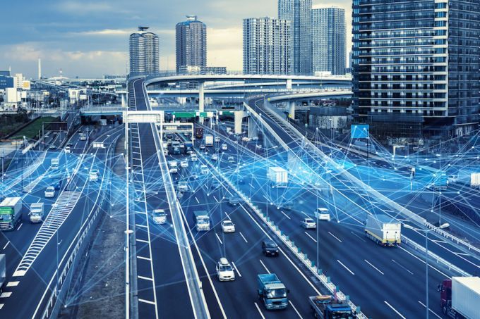 A bustling urban highway with multiple lanes of traffic features digital blue lines overlaying the scene, reminiscent of Digital Twins technology.