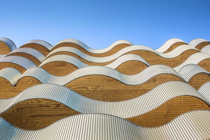 A modern architectural facade showcases wavy, undulating patterns crafted with advanced Rhino skills, blending wood and metal textures. The parametric design creates a rhythmic flow of curves and contrasts, set against a clear blue sky.
