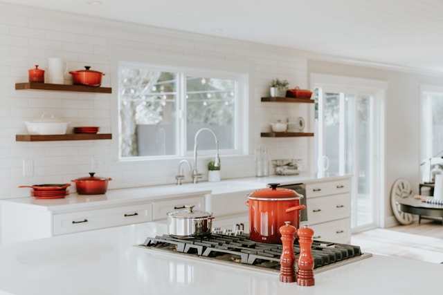 A bright, Vastu compliant kitchen with white cabinetry and a large island exudes warmth.