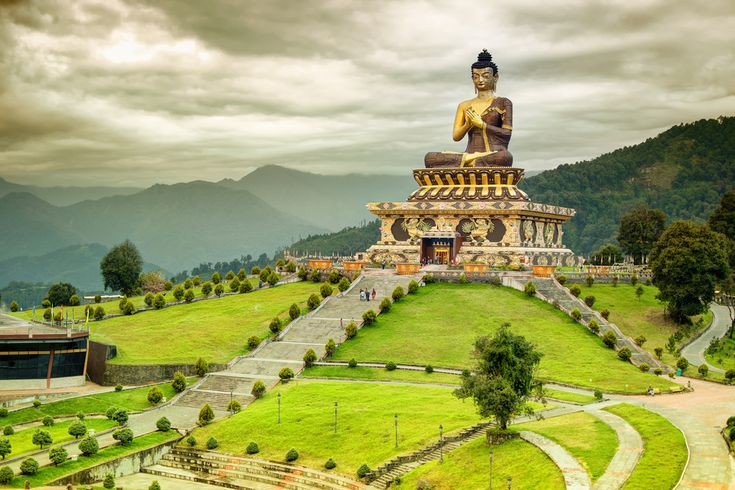 A large Buddha statue sits atop a multi-tiered platform highlights Sikkim's architecture. 